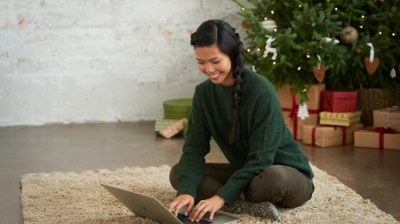 henkilö kannettavan tietokoneen kanssa lattialla jouluisessa miljöössä