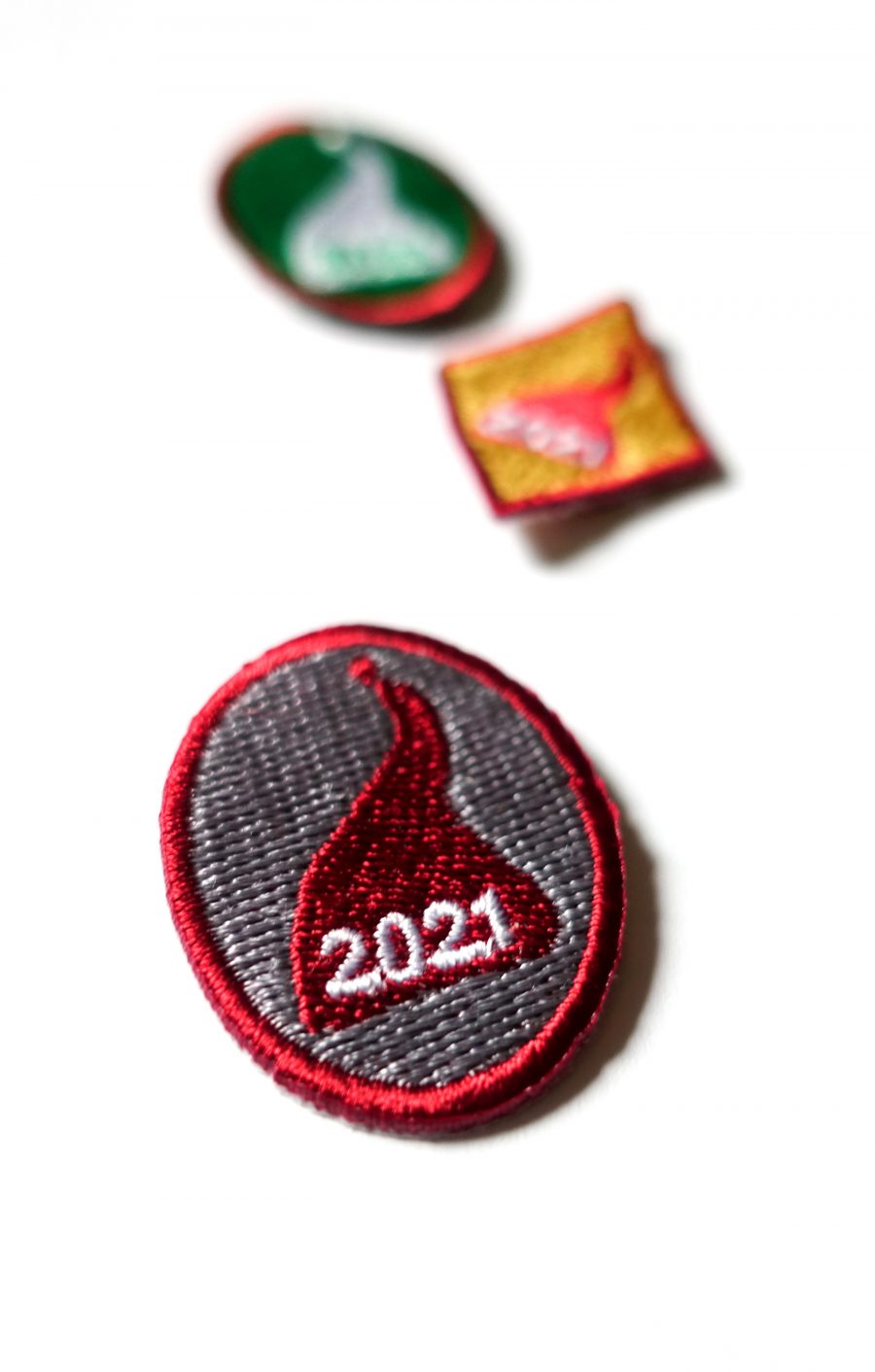 Kolme kangasmerkkiä, joissa tonttulakki ja vuosiluku 2021. Partiolaisten tonttumerkit.