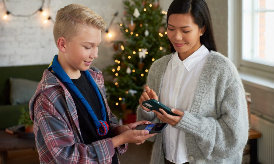 Valokuva: partiolainen huivi kaulassaan ja asiakas suorittamassa adventtikalenterin mobiilimaksua