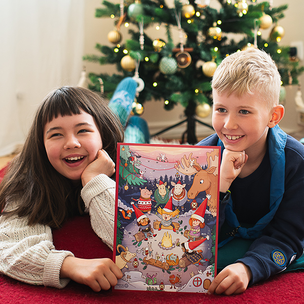 Iloiset lapset partiolaisten adventtikalenterin kanssa joulukuusen edessä.